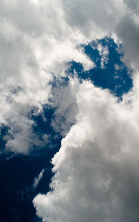 A storm front carving a dark diagonal across deep blue — the original focus on the clouds frame