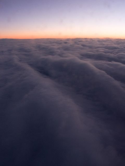 A violet cloud deck from above at dusk, sunset banding the horizon