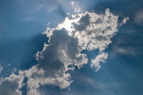 A sunburst behind a dark cloud, rays fanning across the sky