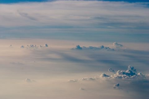 Cumulus towers breaking through a haze layer, seen from a plane