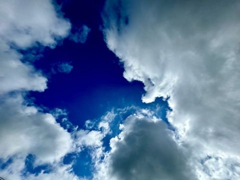 A cobalt hole punched through sculpted cumulus