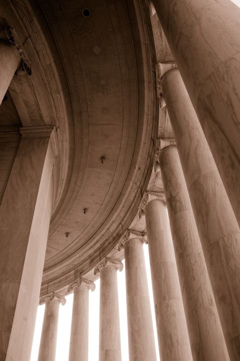 The Jefferson colonnade rising into shadow, bases glowing
