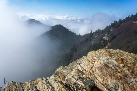 A rocky ridgeline running down into a sea of cloud