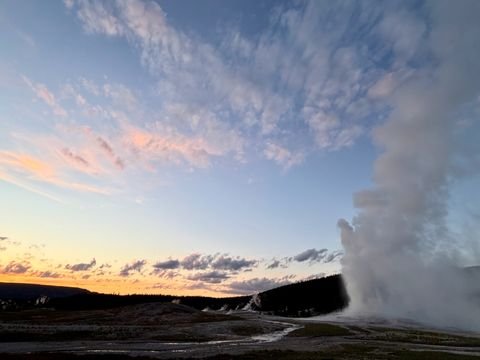 A geyser erupting into a sunset sky