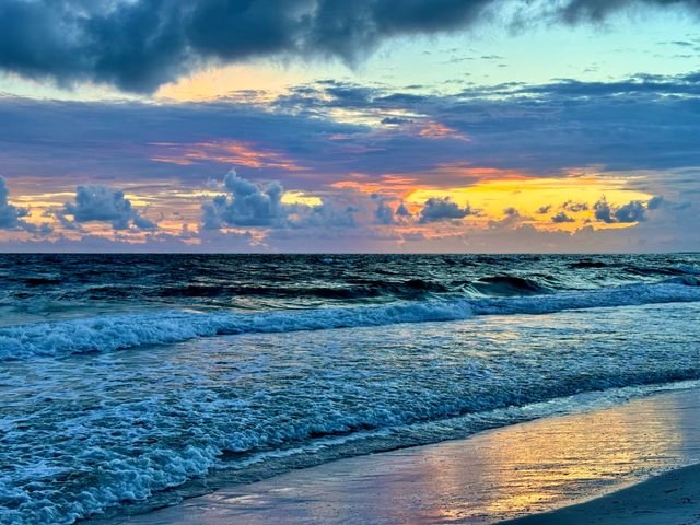 Dawn surf breaking on the beach under a band of yellow horizon light