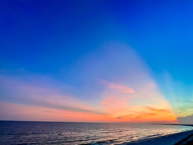 Twilight over the Gulf — a fan of pink cloud above a darkening sea