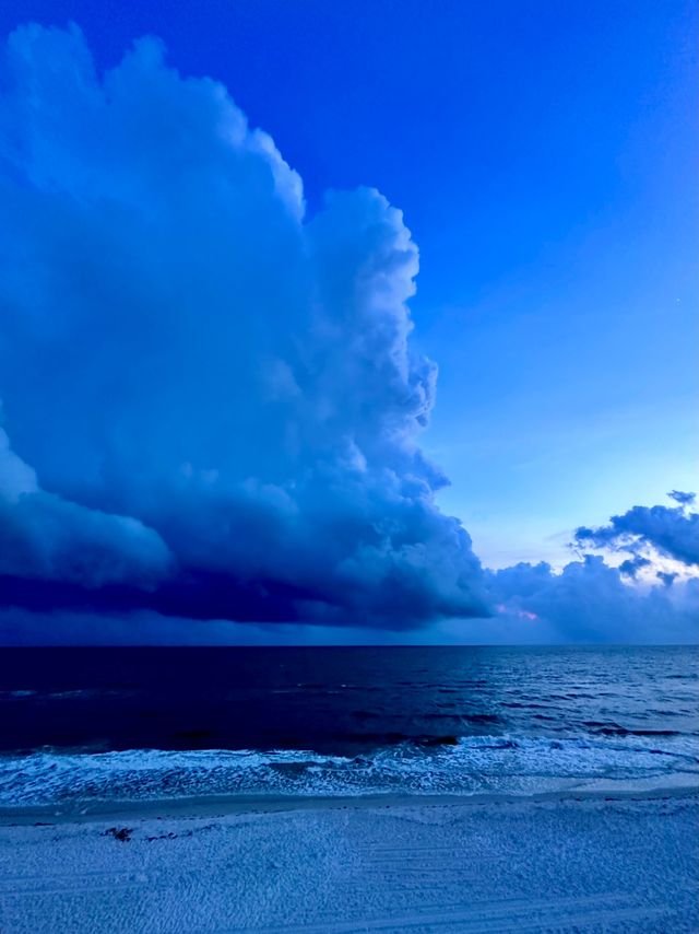 A storm tower over the sea at blue hour, beach in the foreground
